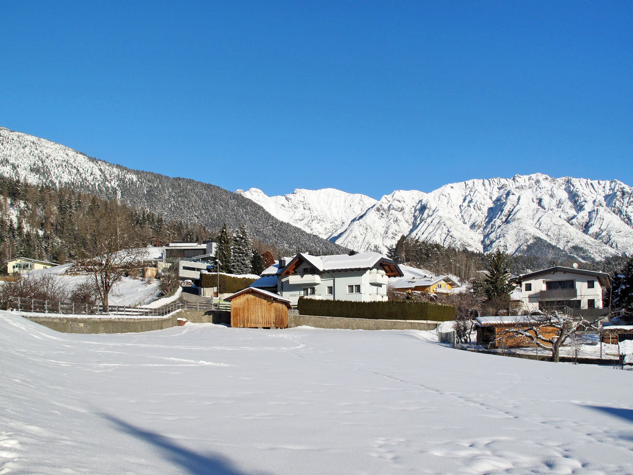 Un pueblo cubierto de nieve con casas y una montaña al fondo.