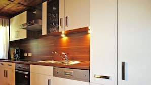 Une cuisine moderne dotée d’appareils électroménagers en acier inoxydable, de meubles de rangement en bois et d’un meuble à vin intégré.
