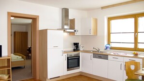 A compact kitchen with white cabinets, a built-in oven, a dishwasher, and a window with a view. - Haus Alina by Interhome (Tux)