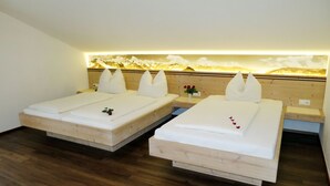 Two single beds with wooden frames and white bedding, a wooden nightstand with a vase of red roses, and a wall-mounted light fixture. - Klammlhof by Interhome (Zell am Ziller)