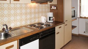 A compact kitchen with a dishwasher, stove, and coffee maker. - Elisabeth by Interhome (Zell am Ziller)