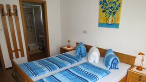 Un lit double avec une literie à rayures bleues, une tête de lit en bois, une table de chevet avec une lampe et un tableau accroché au mur.