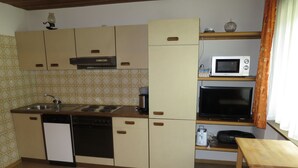 Une cuisine compacte équipée d’un lave-vaisselle, d’une cuisinière, d’un four à micro-ondes et d’une petite table.
