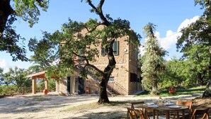 Ein rustikales Steinhaus mit einer Holzpergola und einem Essbereich mit Tisch und Stühlen.