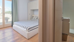 A modern bedroom with a bed, a sliding glass door to a balcony, and a shower area. - La Marina by Interhome (Scarlino)