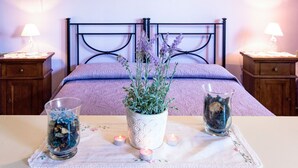 A neatly arranged bedroom with a bed, bedside tables, a bedside lamp, a vase with flowers, and candles on a table. - Monolocale - Ranch Hotel by Interhome (Scarlino)