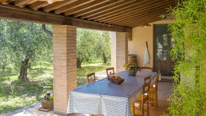An outdoor patio with a table set for dining, surrounded by brick pillars and wooden beams. - Oliveta by Interhome (Cecina)