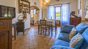 A cozy living room with a sofa, a television, and a dining area with a table and chairs. - Oliveta by Interhome (Cecina)
