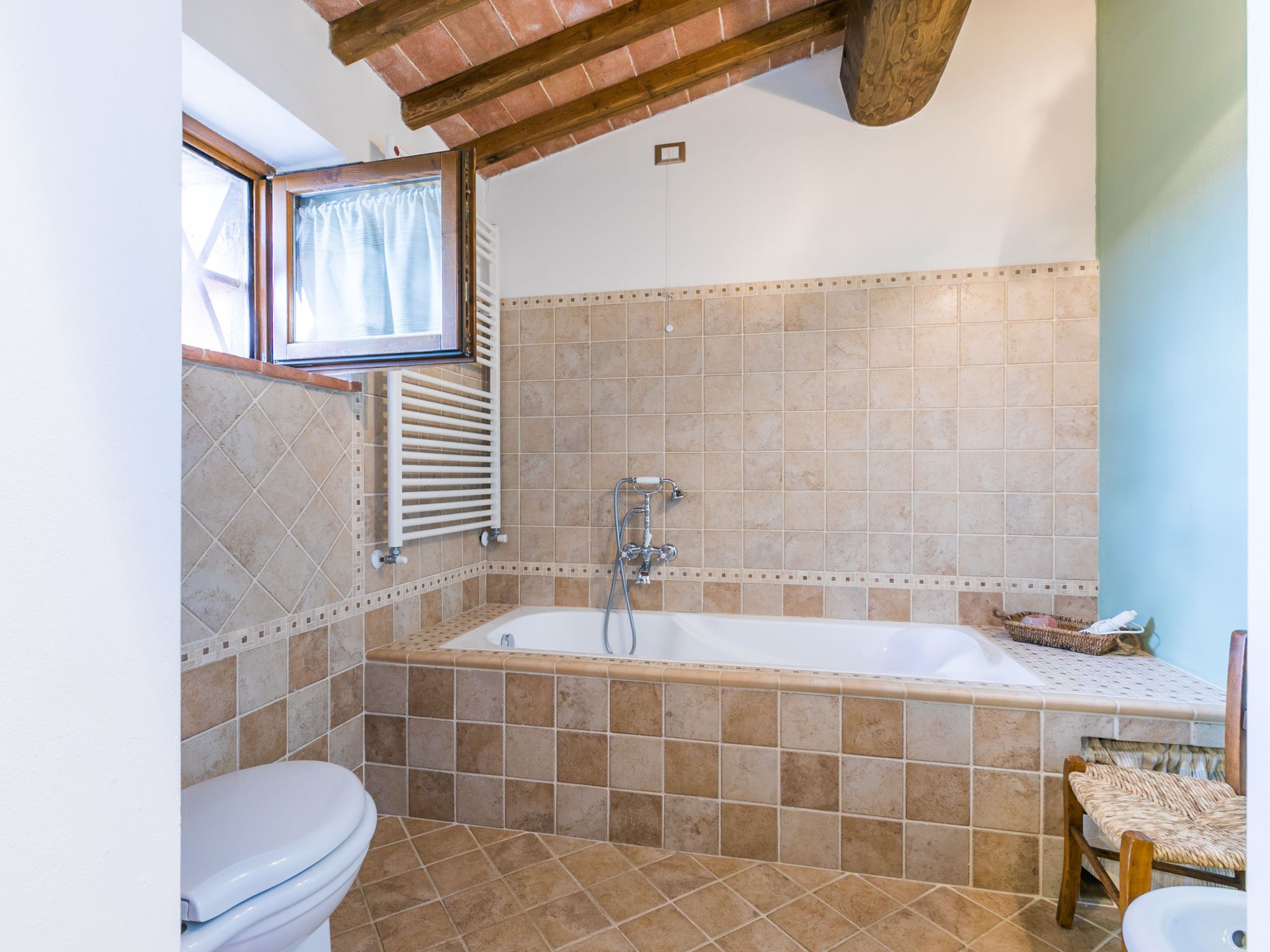 A bathroom with a bathtub, a toilet, and a window.