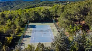 Een tennisbaan omringd door dicht bos en bergen.