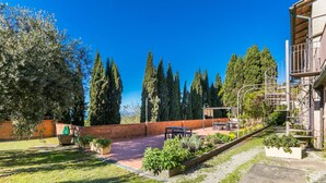 A courtyard with a brick wall, a pergola, and a staircase leading to a wooden building. - San Vivaldo by Interhome (Montaione)
