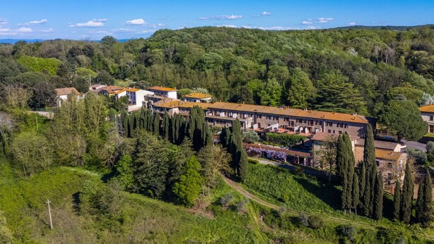 A hillside village with traditional buildings, a central courtyard, and a dense forest backdrop. - San Vivaldo by Interhome (Montaione)