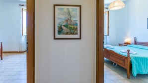 Een slaapkamer met een bed, nachtkastje, lamp en een lijst met een schilderij aan de muur.