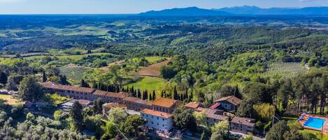 A villa with a swimming pool, surrounded by lush greenery and hills.