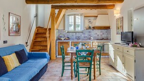 A cozy kitchen with a dining area, wooden beams, and a blue sofa. - Villetta by Interhome (Colle Val d'Elsa)