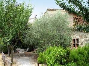 A garden with a table and chairs, a tree, and a building with a lattice window. - Antico Borgo S Lorenzo Ginestra by Interhome (Colle Val d'Elsa)
