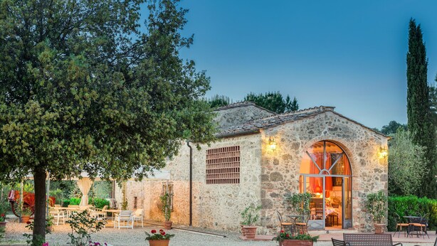 A stone building with a large arched entrance, outdoor seating, and potted plants. - Antico Borgo S Lorenzo Cipresso by Interhome (Colle Val d'Elsa)