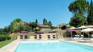A swimming pool with lounge chairs and umbrellas, surrounded by stone buildings and trees. - Antico Borgo S Lorenzo Cipresso by Interhome (Colle Val d'Elsa)