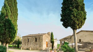A stone building with a rustic facade, surrounded by tall cypress trees and a gravel path. - Antico Borgo S Lorenzo Cipresso by Interhome (Colle Val d'Elsa)
