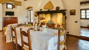A dining area with a stone fireplace, wooden ceiling beams, and a rustic ambiance. - Antico Borgo S Lorenzo Cipresso by Interhome (Colle Val d'Elsa)