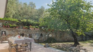 A patio with a table set for dining, surrounded by stone walls and potted plants. - Vacation home Casali by Interhome (Strettoia)