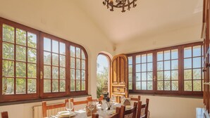 A dining room with a large table set for six, large windows, and a chandelier. - Vacation home Casali by Interhome (Strettoia)