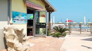 Un centre de plongée avec une enseigne, une entrée abritée et une piscine en arrière-plan.