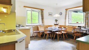 Une cuisine moderne avec un coin repas, de grandes fenêtres et une vue sur la verdure.