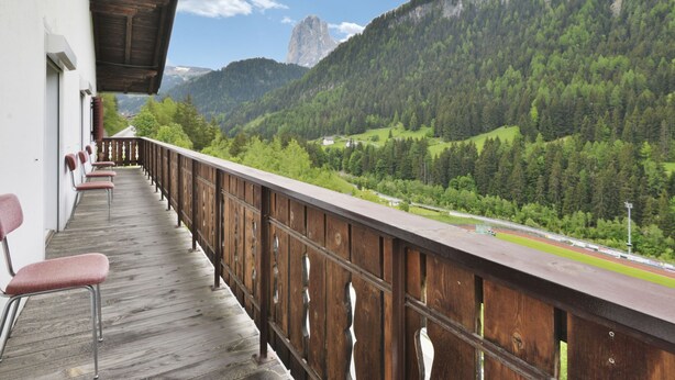 Un balcon doté de balustrades en bois, offrant une vue sur un paysage montagneux.