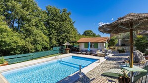 A swimming pool with a wooden deck, lounge chairs, and a small building with a tiled roof. - Apartment Viliam by Interhome (Rovinj)