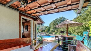 An outdoor patio with wooden furniture, a pool, and a view of the surrounding garden. - Apartment Viliam by Interhome (Rovinj)