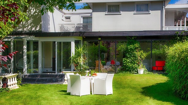 A spacious outdoor patio with a covered seating area, surrounded by lush greenery and a well-maintained lawn. - Apartment Duhnen by Interhome (Cuxhaven)