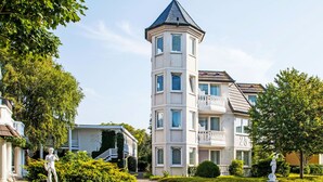 A multi-story building with a tower, a statue in the front garden, and a well-maintained lawn. - Apartment Duhnen by Interhome (Cuxhaven)
