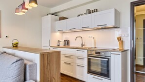 A modern kitchen with white cabinets, a wooden countertop, and a built-in oven. - Horní Mísečky by Interhome (Horni Misecky)