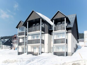 Ein mehrstöckiges Hotel mit Balkonen und einem Skiabhang im Hintergrund.
