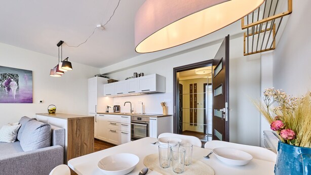 A modern kitchen with white cabinets, a built-in oven, and a dining area with a white table set for four. - Horní Mísečky by Interhome (Horni Misecky)