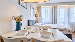 A modern hotel room with a dining area, a bed with a grey headboard, and large windows with sheer curtains. - Horní Mísečky by Interhome (Horni Misecky)