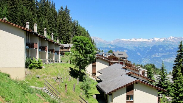 Un hotel su una collina con diversi edifici, ognuno dotato di balconi e vista sulle montagne circostanti.