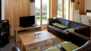 A cozy living room with a leather sofa, a wooden coffee table, and a television on a wooden stand. - Edelweiss by Interhome (Thyon-Les Collons)