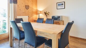 A wooden-paneled room with a large table, six chairs, a lamp, a framed picture, and a microwave. - Edelweiss by Interhome (Thyon-Les Collons)