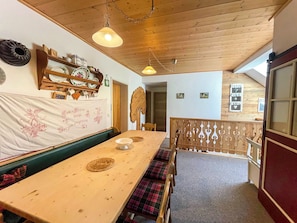 Un comedor de madera con bancos, una mesa larga y una pared decorativa con platos y un estandarte.