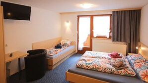Habitación de hotel con dos camas individuales, un escritorio, una silla, un televisor y una ventana con cortinas.