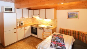 Una cocina pequeña con armarios de madera, un microondas, una estufa y un lavamanos.