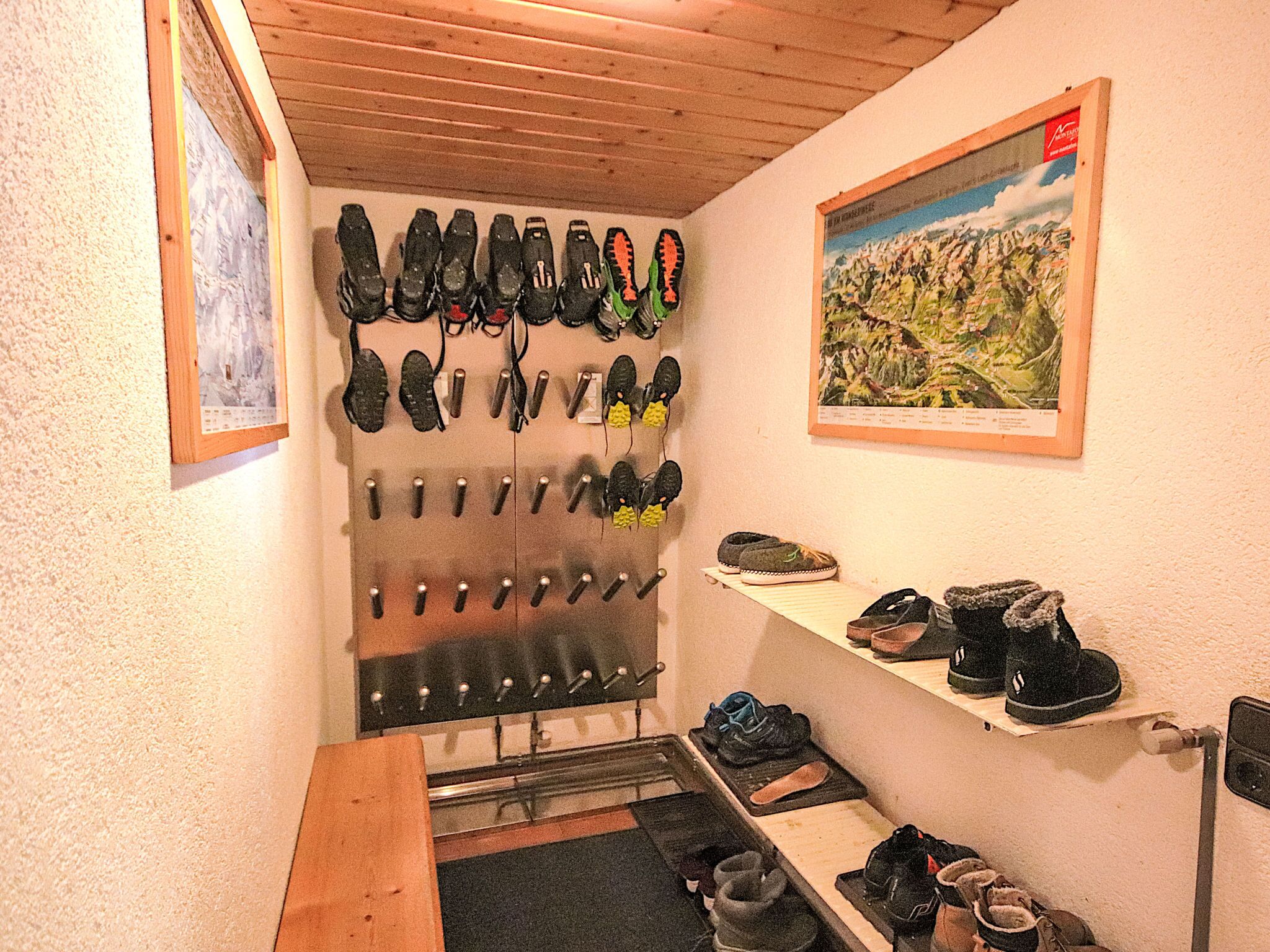 A hallway with a shoe rack holding various types of footwear, a shelf with additional shoes, and a framed picture on the wall.