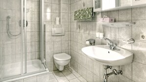 A modern bathroom with a glass shower enclosure, a toilet, a sink with a mirror above, and a towel rack. - Landhaus Heim by Interhome (Zell am Ziller)