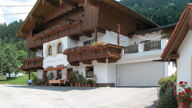 A traditional Alpine building with wooden balconies, a sign reading "Landhaus Neim", and a garage. - Landhaus Heim by Interhome (Zell am Ziller)