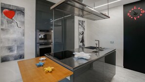 A modern kitchen with a central island, stainless steel appliances, and a wall-mounted clock.