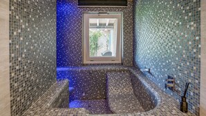 A bathroom with mosaic tile walls, a window, and a bathtub.