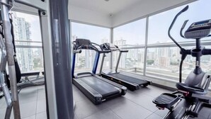 A gym with treadmills and a stair climber, large windows with a city view.