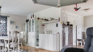 A spacious living room with a wooden floor, a grey sofa, and a dining area with white cabinets and a table. - Enerhögen Flädern by Interhome (Bullaren)